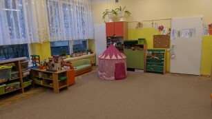sala z przedszkola z wiszącym zamkiem w kolorze różowym obok półki z zabawkami