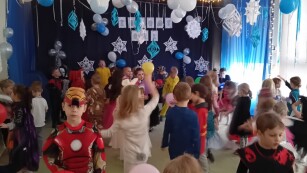dzieci w kostiumach tańczą podczas balu w udekorowanej sali w kolorze niebieskim